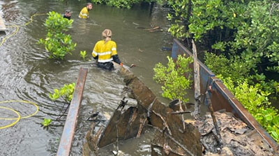 Workers in the water removing debris from a barge 